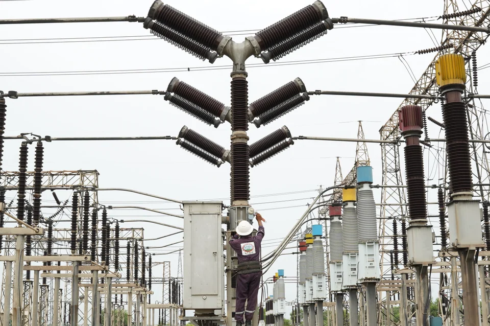 A technician working among high-voltage equipment in a grid station