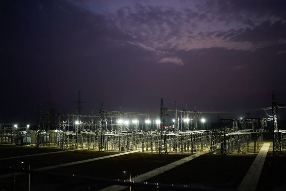 Floodlights illuminating a substation beneath a purple-blue dusk sky
