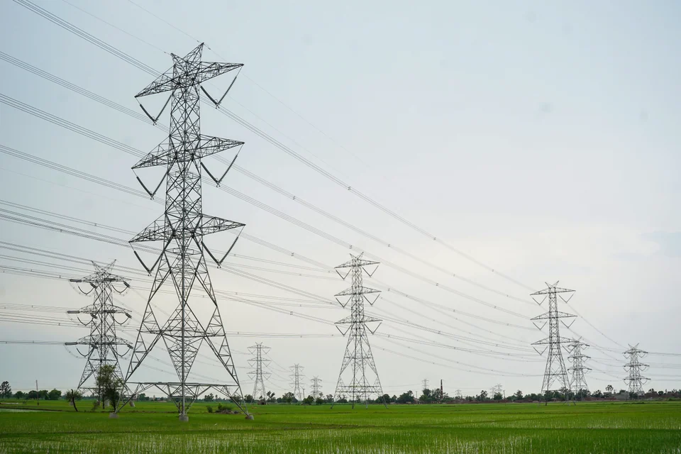 Steel transmission towers and conductors crossing green agricultural fields
